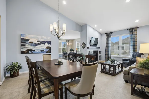a dining room with wooden floor a chandelier a glass table and chairs