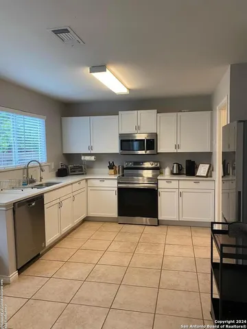 a kitchen with a sink a stove top oven and white cabinets