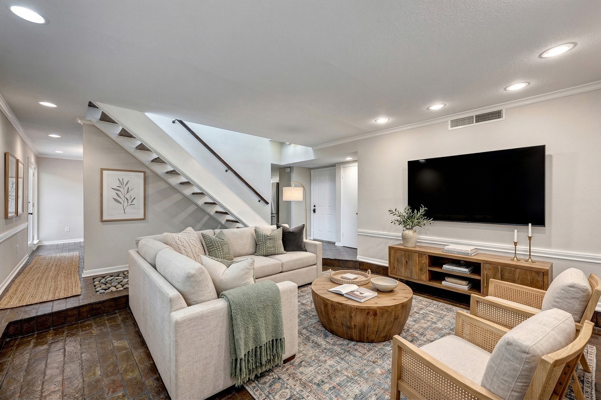 Virtually Staged. Large brick floored step down living room looking toward entry in center and on left the walk into the dining room. Downstairs floors in main living areas are all the same beautiful glossy brick.