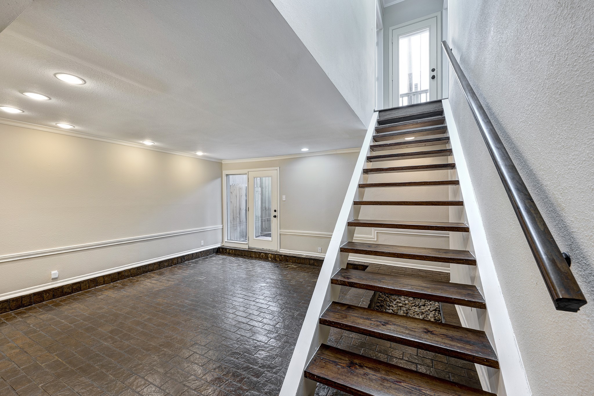 1122 Autrey Street, Unit 5 Houston, TX 77006 - Photo 11 of 32 Living room view w/stairs on right. Entry view of step down living room with beautiful brick flooring and modern open staircase to the upstairs bedrooms and bath. Note door in left rear to patio.