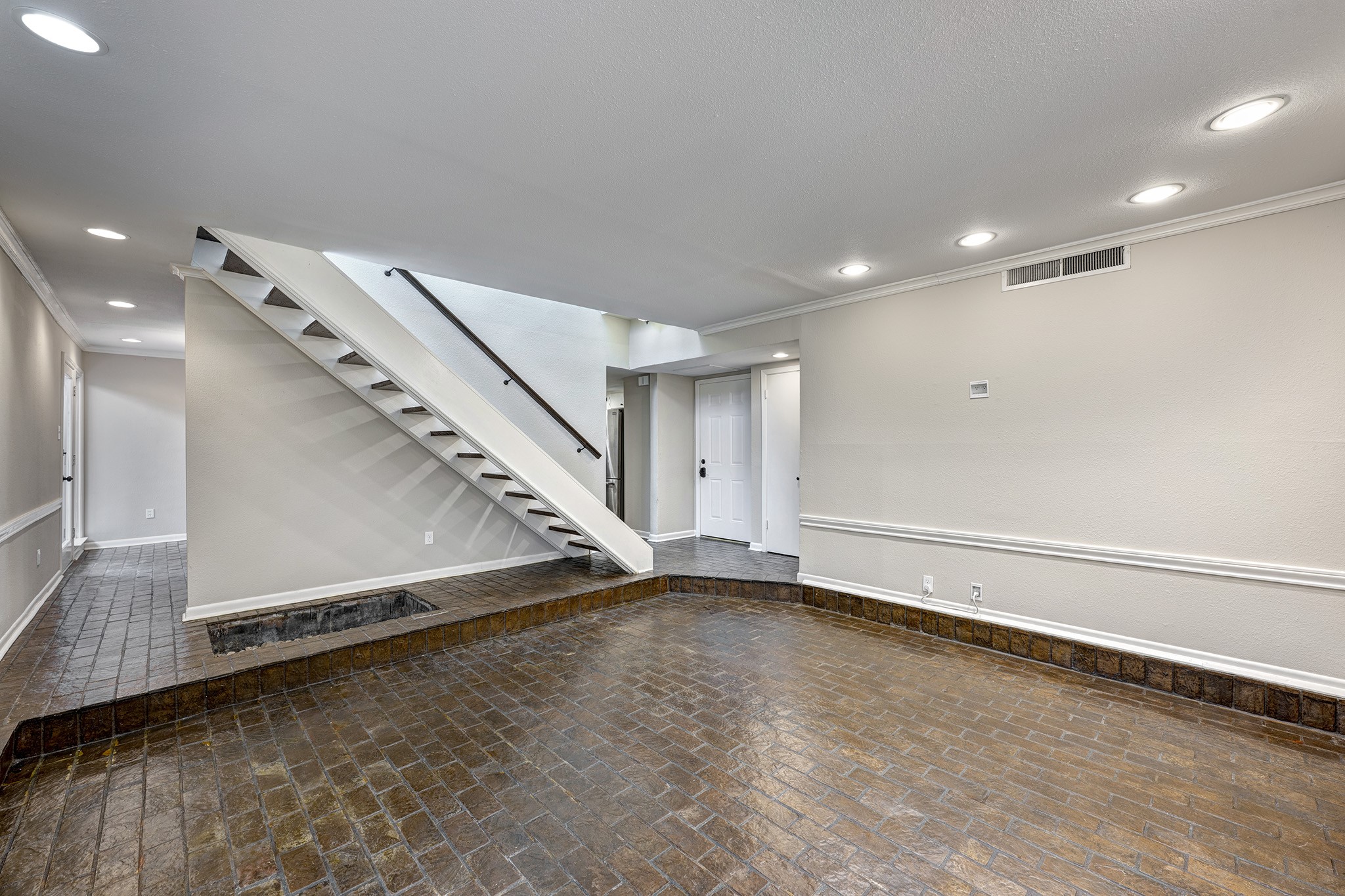 1122 Autrey Street, Unit 5 Houston, TX 77006 - Photo 2 of 32 Large brick floored step down living room looking toward entry in center and on left the walk into the dining room. Downstairs floors in main living areas are all the same beautiful glossy brick.