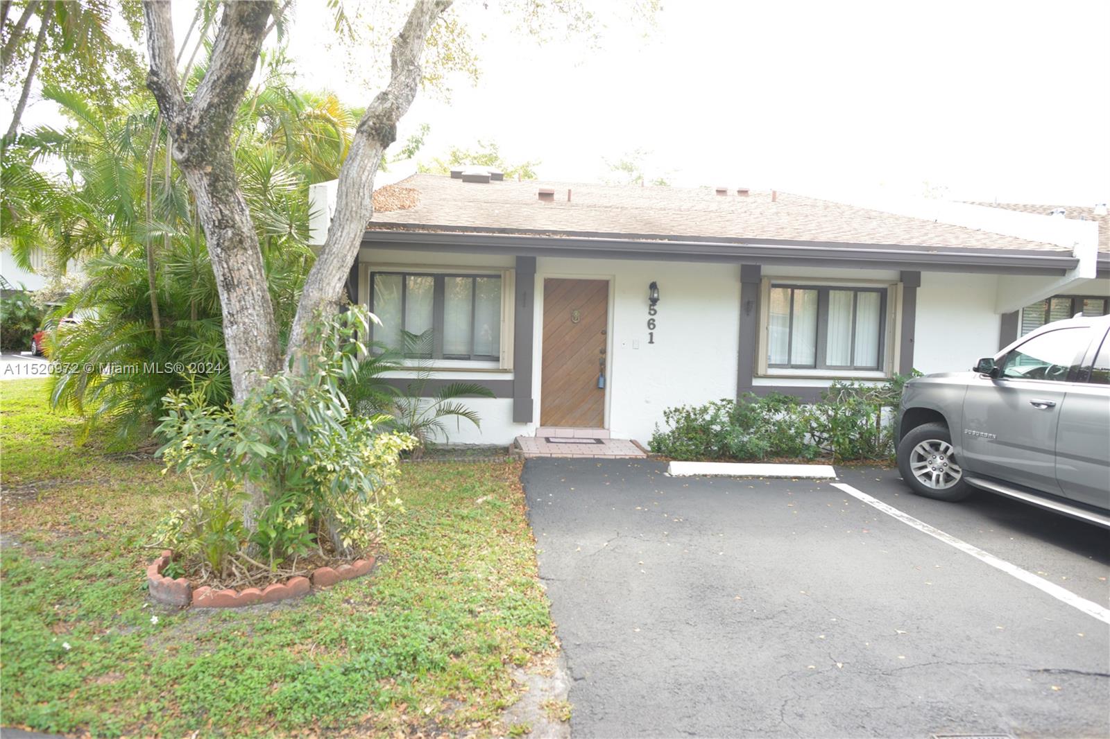 a view of a white house next to a yard with potted plants