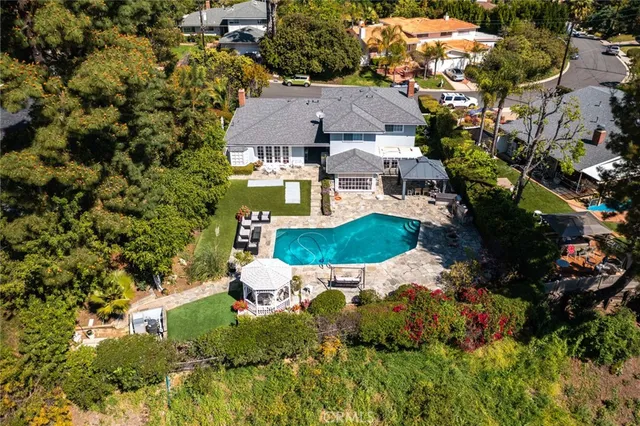 an aerial view of residential houses with outdoor space and trees all around