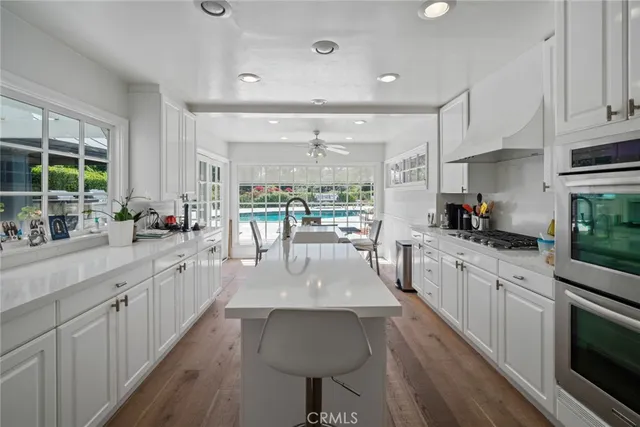 a kitchen with stainless steel appliances granite countertop a table chairs sink and cabinets