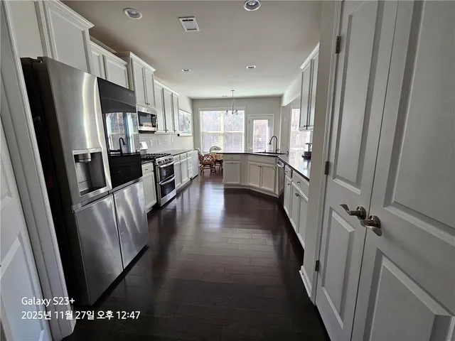 a view of a kitchen with refrigerator and wooden floor