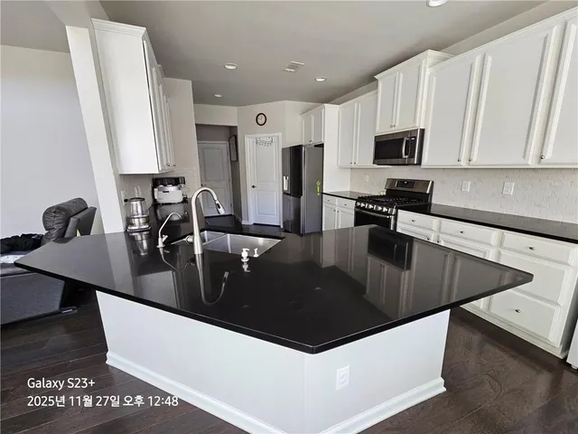 a kitchen with stainless steel appliances granite countertop a sink a stove and a microwave