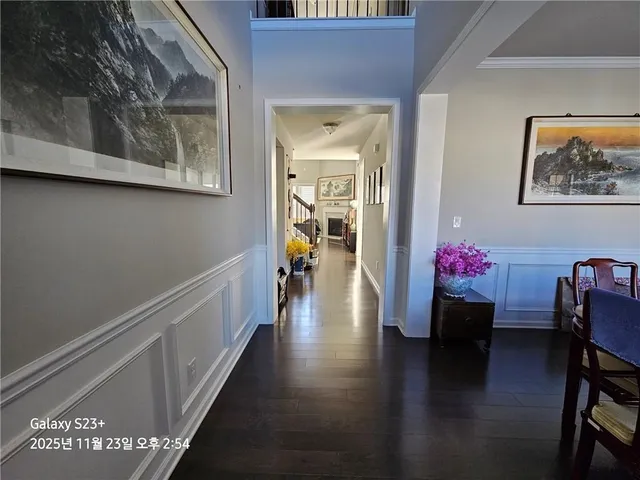 a hallway with wooden floor and a dining table