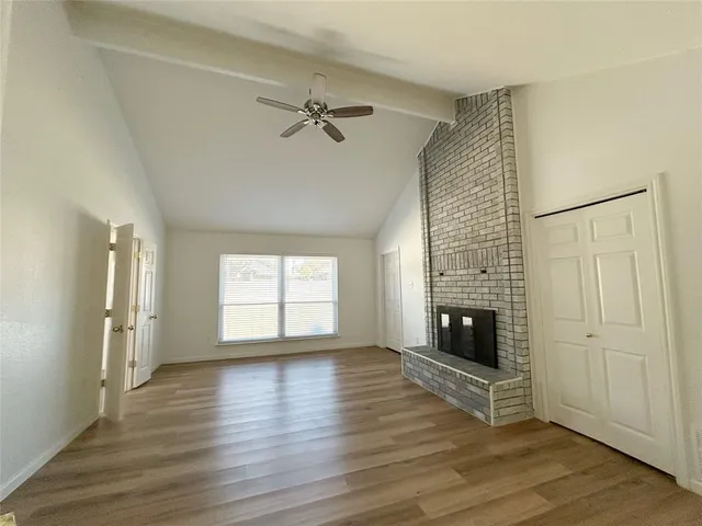 a view of an empty room with a fireplace and a window