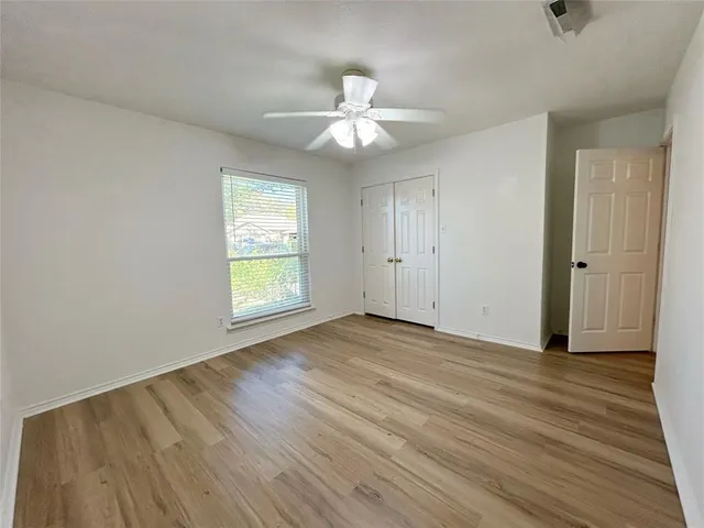an empty room with wooden floor chandelier fan and windows