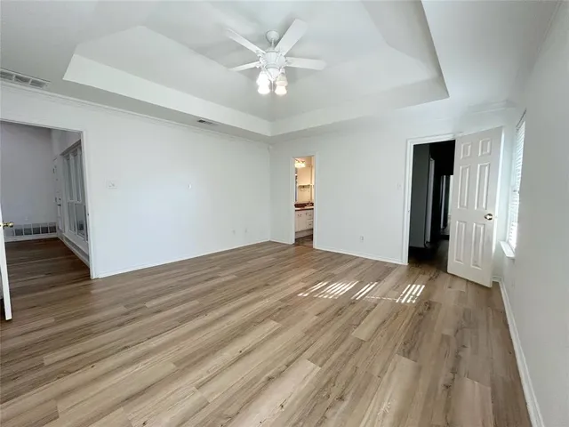 an empty room with wooden floor and ceiling fan