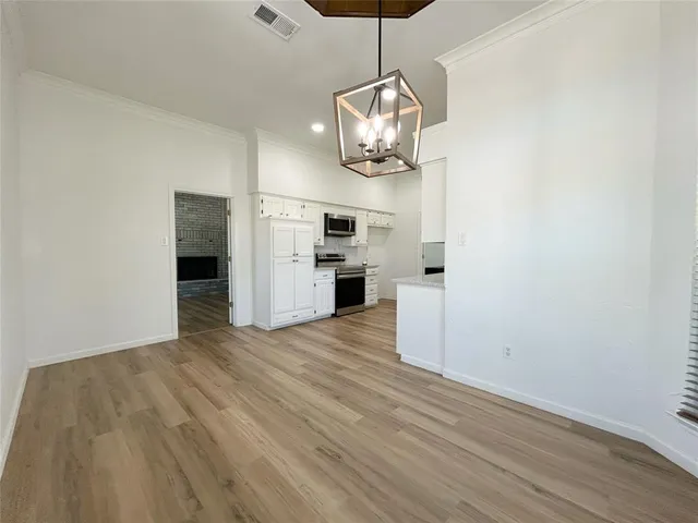 a view of empty room with wooden floor and kitchen view