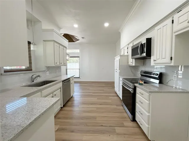 a large kitchen with stainless steel appliances granite countertop a lot of counter space and wooden floors