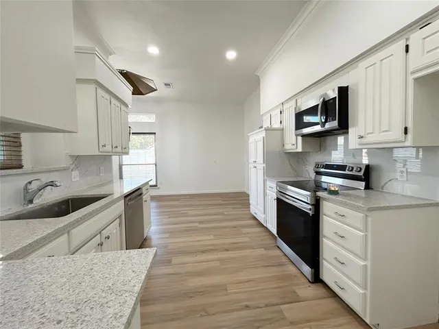a large kitchen with stainless steel appliances granite countertop a sink and a stove