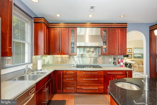 a kitchen with stainless steel appliances granite countertop a sink a stove and a granite counter tops with large windows