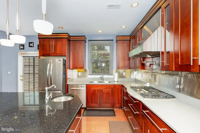 a kitchen with stainless steel appliances granite countertop a stove a sink and a refrigerator