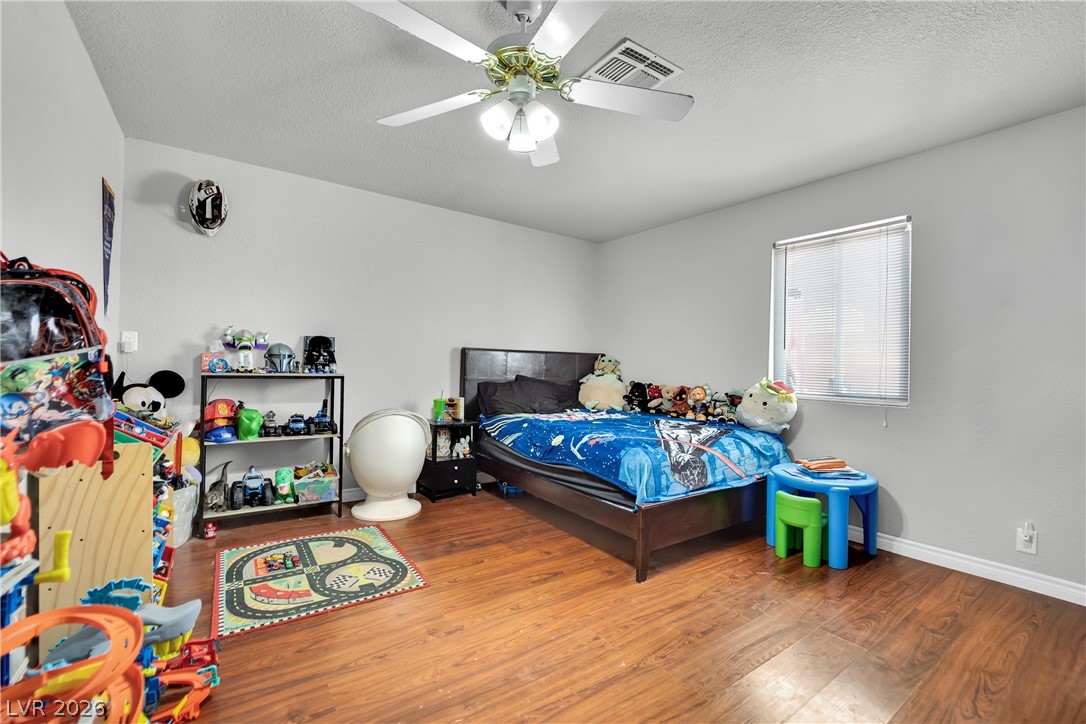 420 North Racetrack Road Henderson, NV 89015 - Photo 35 of 52 Hardwood flooring extends throughout this naturally illuminated bedroom, offering a clean and inviting atmosphere.