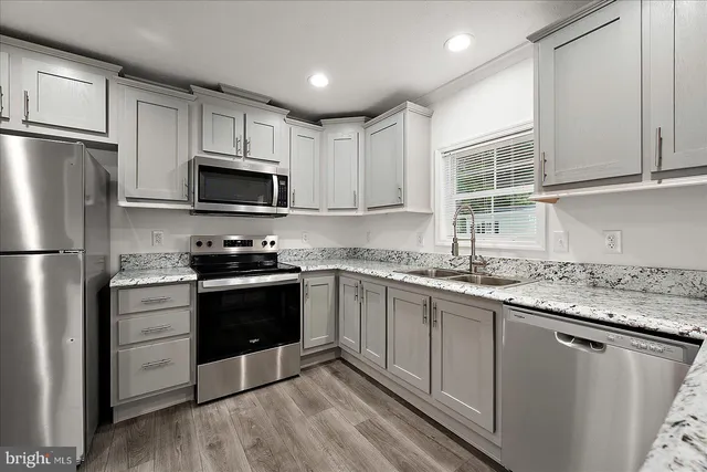 a kitchen with granite countertop a sink cabinets stainless steel appliances and a window