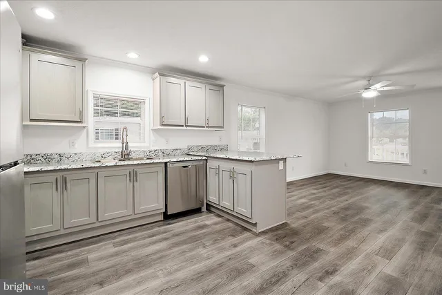 a kitchen sink with granite countertop a sink and cabinets next to a window