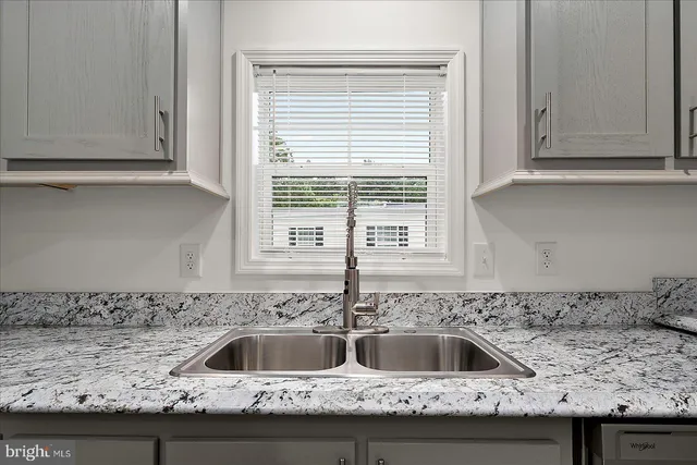 a large kitchen with granite countertop a stove top oven a sink a dishwasher and a white cabinets with wooden floor