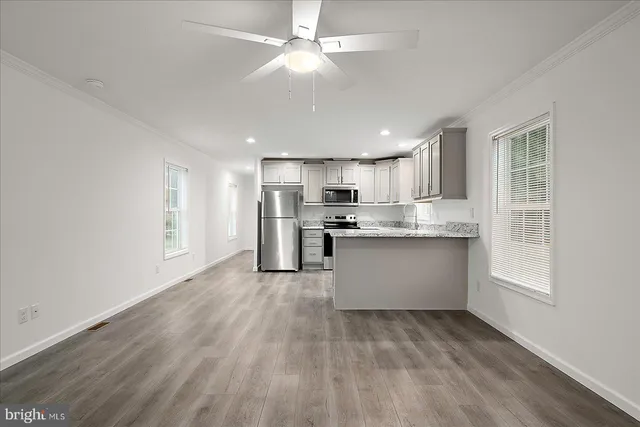 a kitchen with stainless steel appliances granite countertop a stove a sink dishwasher a refrigerator and white cabinets with wooden floor