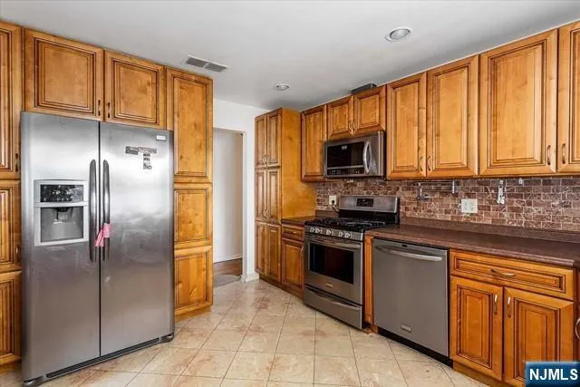 a kitchen with stainless steel appliances granite countertop a refrigerator a stove a sink and dishwasher