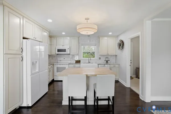a kitchen with stainless steel appliances granite countertop a dining table chairs refrigerator and cabinets