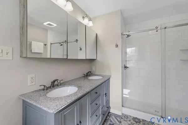a bathroom with a granite countertop sink a mirror and shower