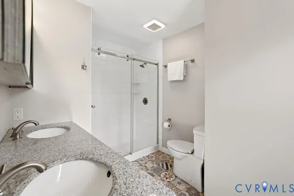 a bathroom with a granite countertop sink toilet and shower