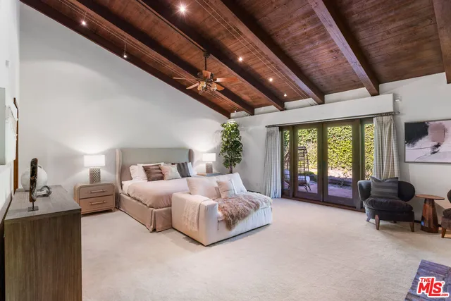 a spacious bedroom with a bed couch chandelier and a large window