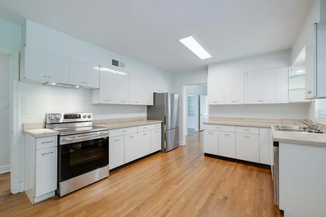 a kitchen with granite countertop white cabinets and stainless steel appliances