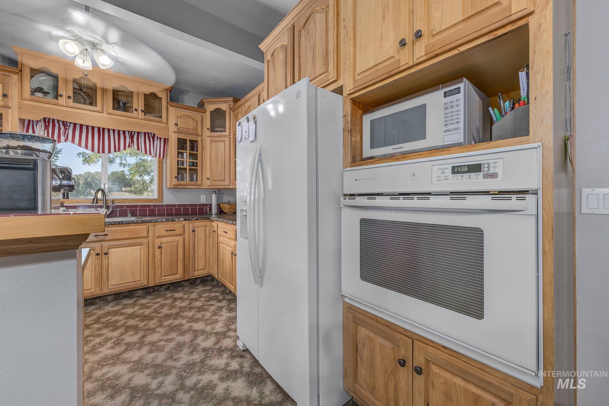 6040 Adams Road New Plymouth, ID 83655 - Photo 15 of 50 Kitchen with white appliances, dark colored carpet, and glass insert cabinets