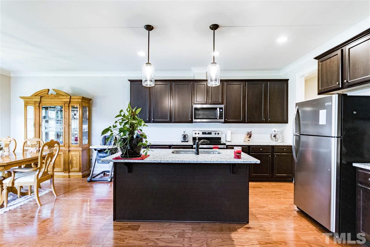 6401 Riley Hill Road Wendell, NC 27591 - Photo 11 of 23 a kitchen with stainless steel appliances kitchen island granite countertop a refrigerator a sink dishwasher a stove and a dining table with wooden floor