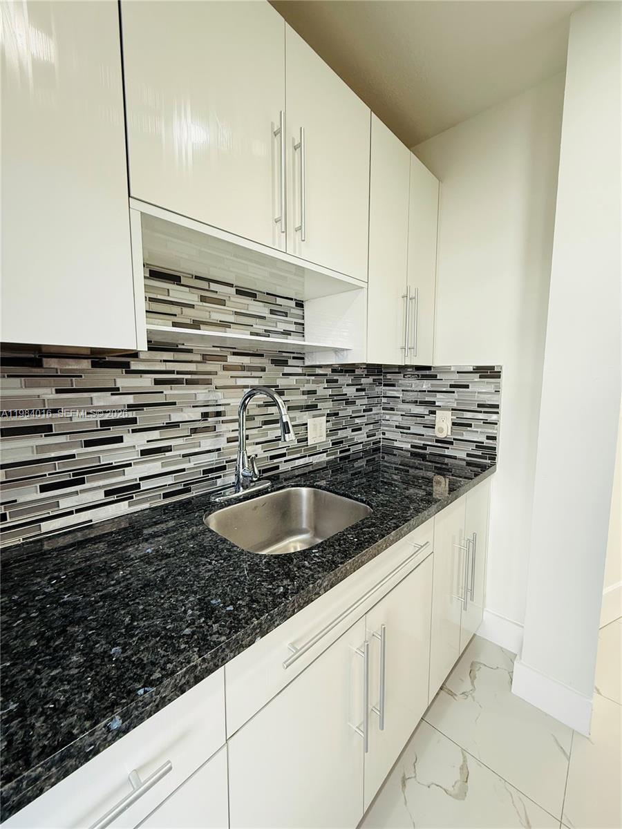 617 Southwest 11th Street, Unit 14E Miami, FL 33129 - Photo 7 of 16 a kitchen with granite countertop a sink and a stove
