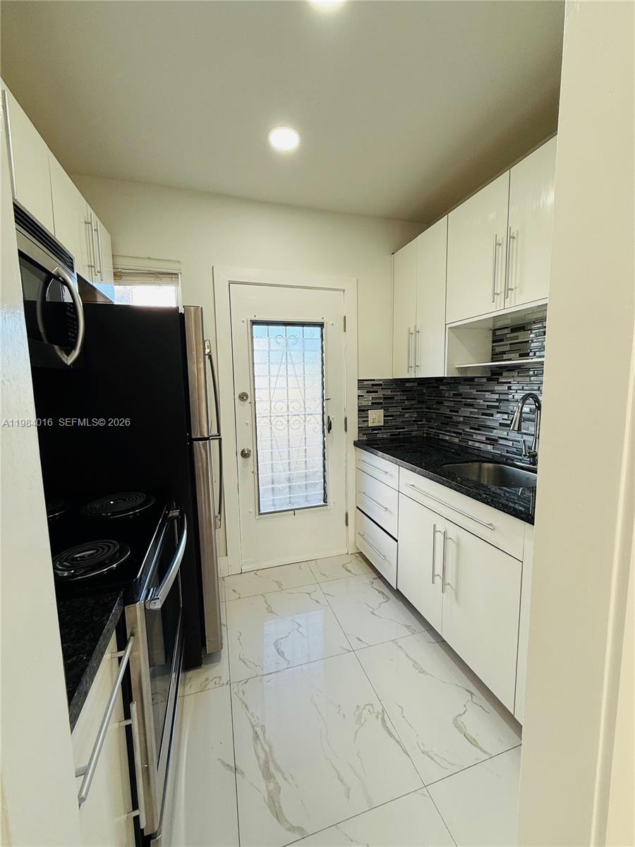 617 Southwest 11th Street, Unit 14E Miami, FL 33129 - Photo 8 of 16 a kitchen with granite countertop a refrigerator and a stove top oven