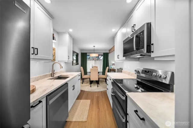 a kitchen with stainless steel appliances granite countertop a stove top oven a sink a counter space and cabinets