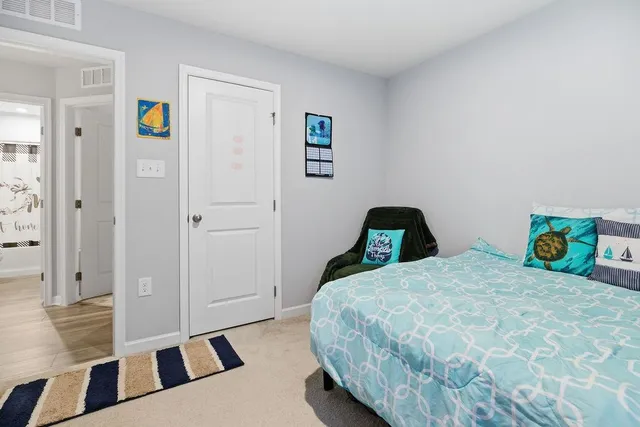 a bedroom with a bed and a lamp on dresser