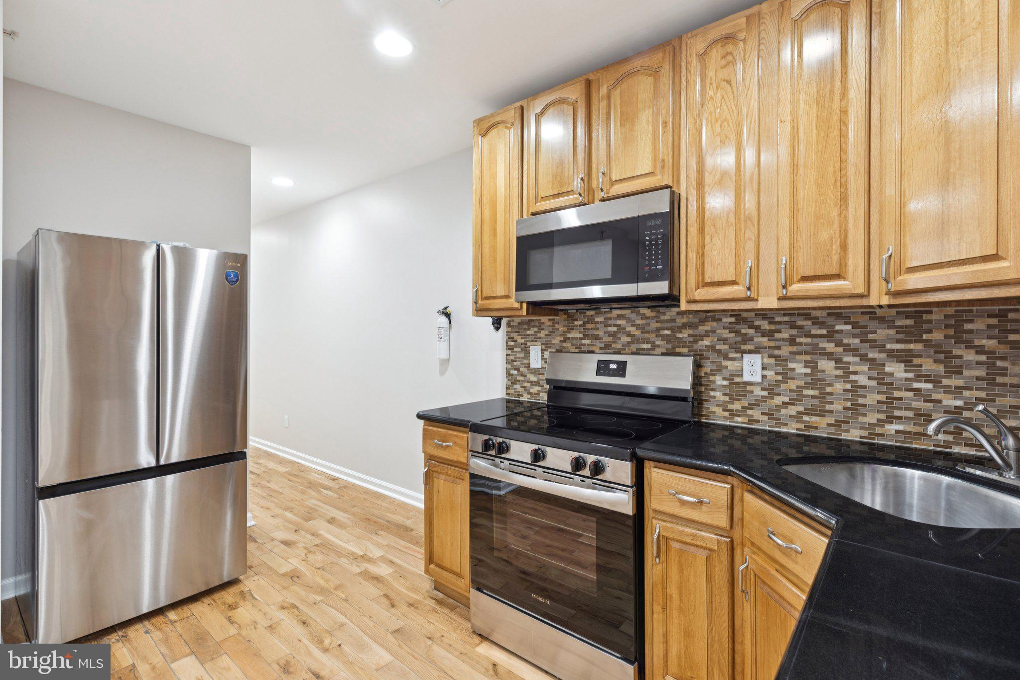 1931 North Uber Street, Unit 2 Philadelphia, PA 19121 - Photo 12 of 26 a kitchen with granite countertop a refrigerator stove and microwave