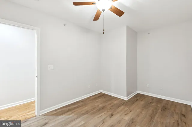 an empty room with chandelier fan and windows