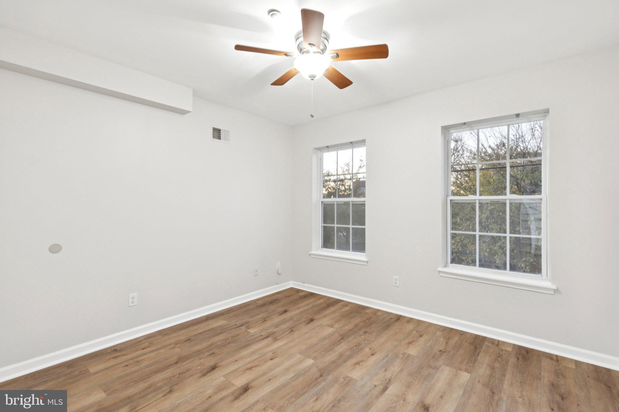 1931 North Uber Street, Unit 2 Philadelphia, PA 19121 - Photo 8 of 26 an empty room with wooden floor chandelier fan and windows