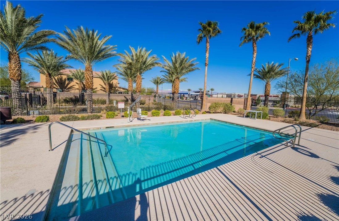 55 Canopus Ridge Way Las Vegas, NV 89183 - Photo 26 of 26 An inviting community pool awaits, framed by graceful palm trees and a bright blue sky.