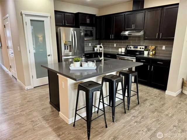 a kitchen with stainless steel appliances granite countertop a table chairs refrigerator and sink