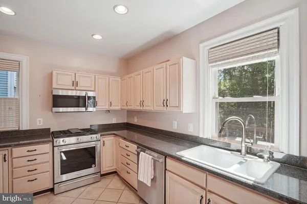 a kitchen with granite countertop a sink stainless steel appliances and cabinets