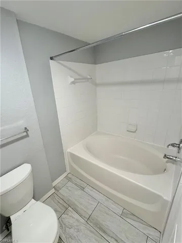 a white toilet sitting next to a bath tub