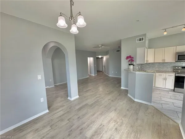 a kitchen with stainless steel appliances granite countertop a refrigerator a sink dishwasher a stove and white cabinets with wooden floor