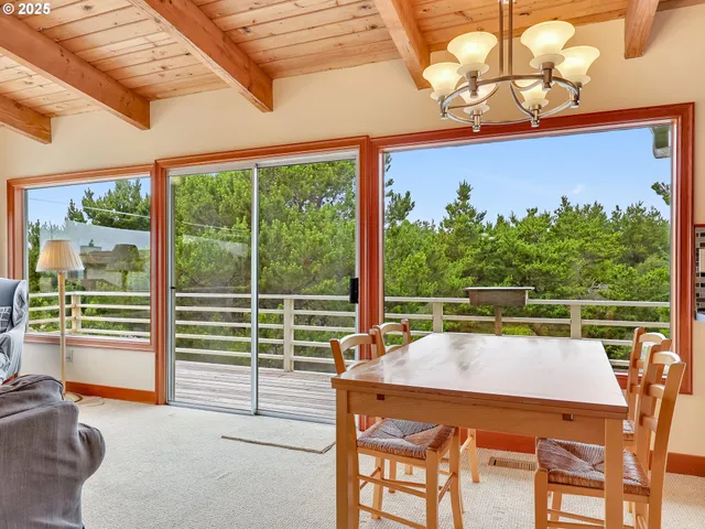 a kitchen with stainless steel appliances granite countertop a stove a sink a refrigerator with a dining table and chairs with the ocean view