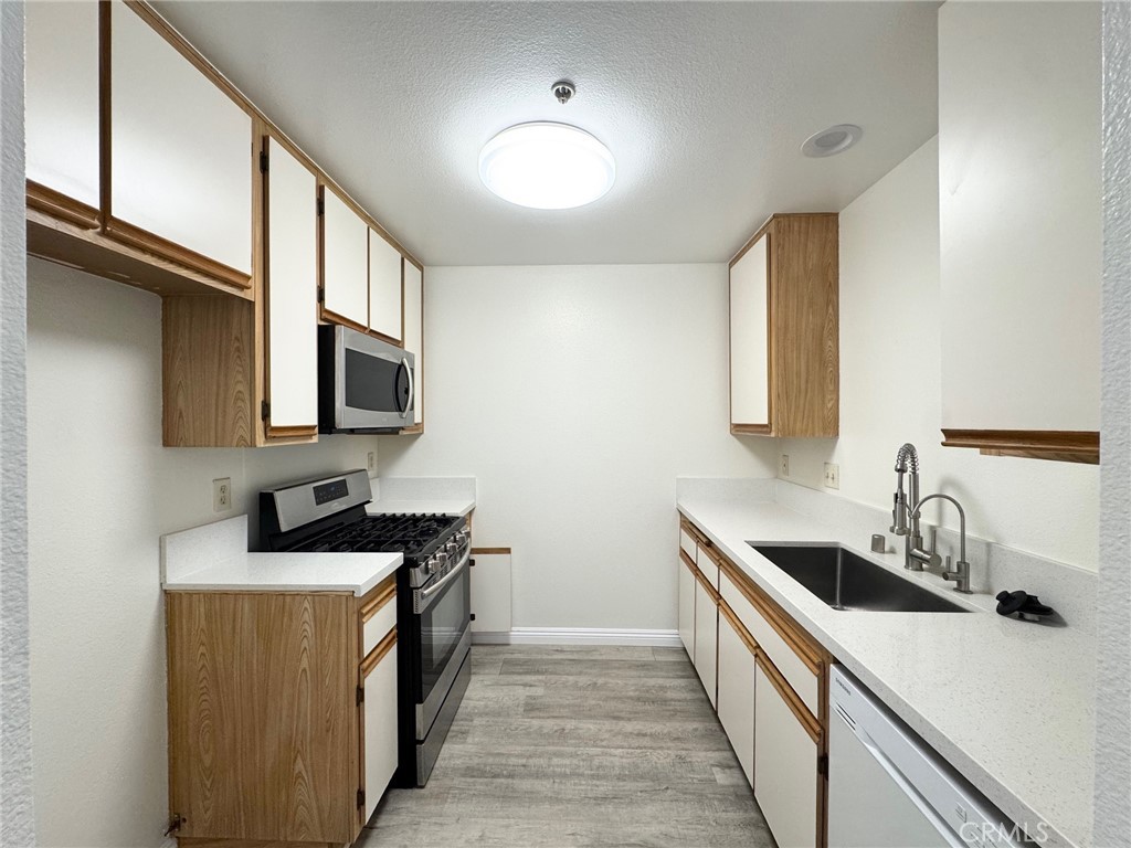 17511 Newland Street, Unit D Huntington Beach, CA 92647 - Photo 6 of 15 a kitchen with a sink stove top oven and cabinets