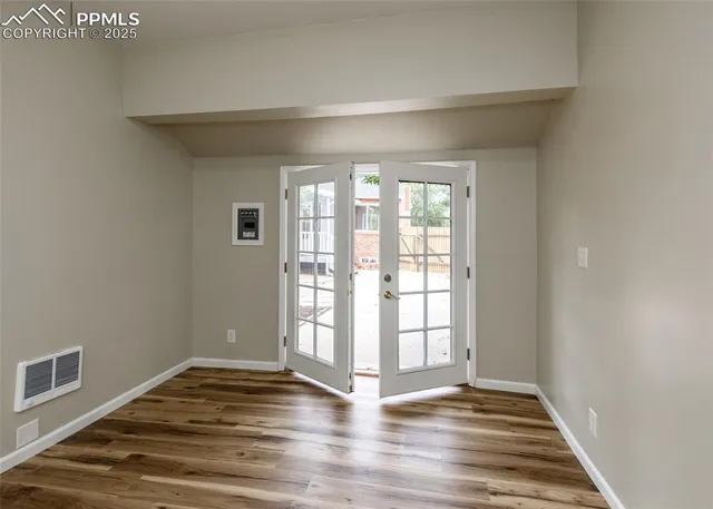 a view of an empty room with wooden floor and a window