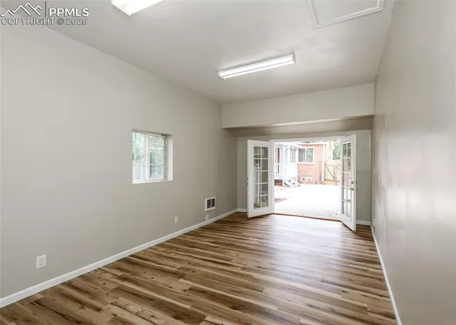 a view of an empty room with wooden floor and a window