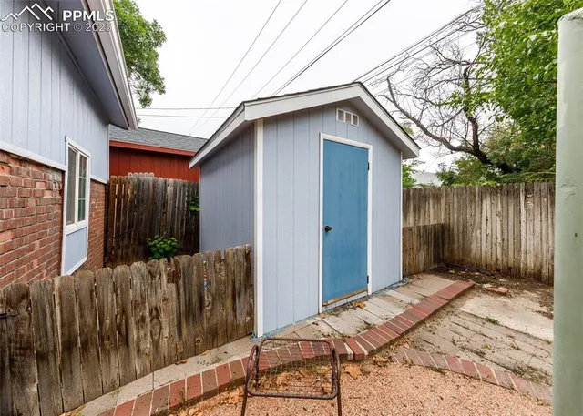 a backyard of a house with a small barn and wooden fence