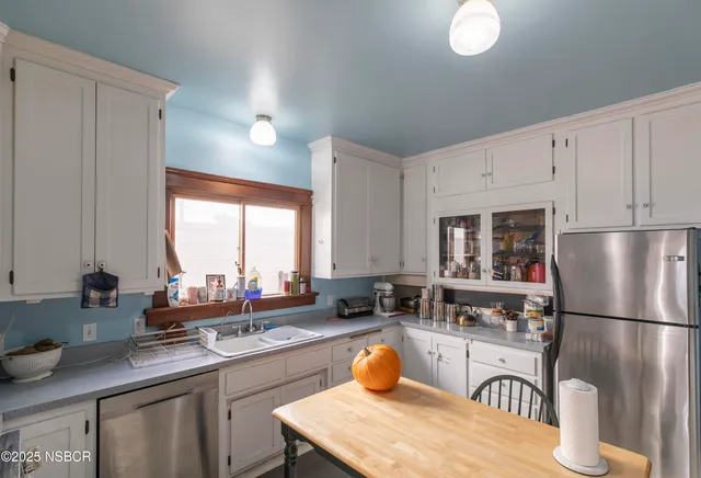 a kitchen with stainless steel appliances granite countertop a sink a stove a refrigerator a center island a dining table and chairs